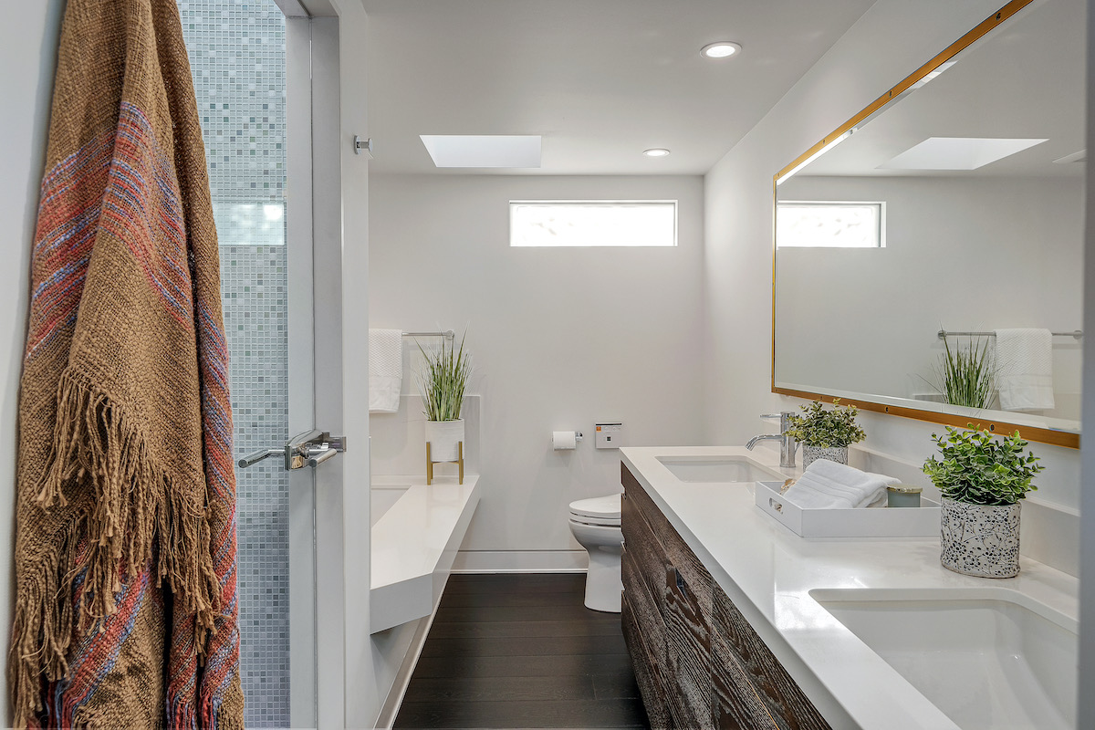 bathroom with tub, shower, and white countertop with dual sinks and a large mirror