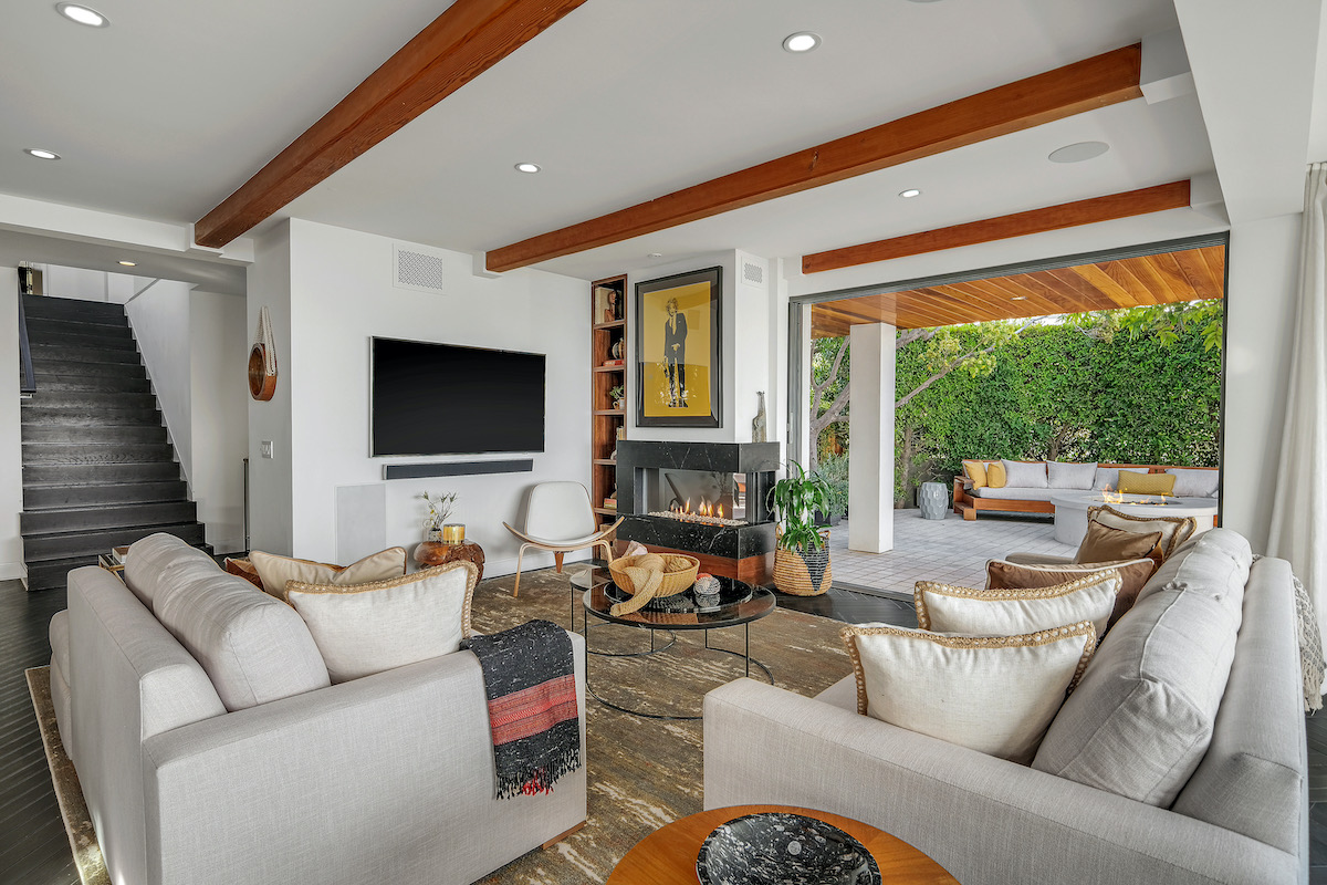 living room with two grey couches, a fireplace, staircase, and open area seating area with a third couch