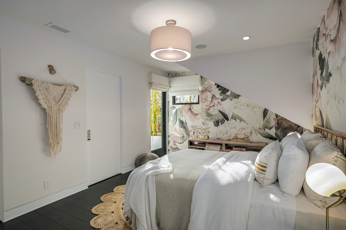 bedroom with floral wallpaper and white walls, with a door leading to the outdoor patio