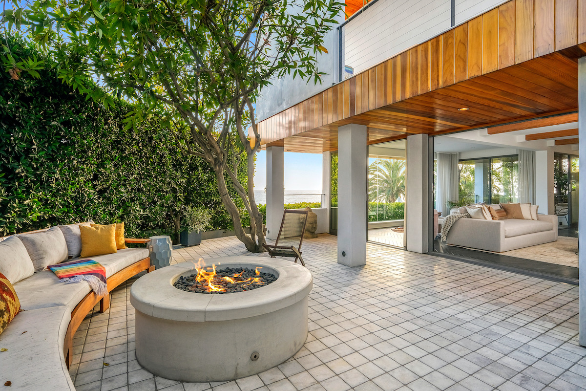 outdoor patio with couch and circular fireplace, with an open floor plan into an indoor living area with a couch