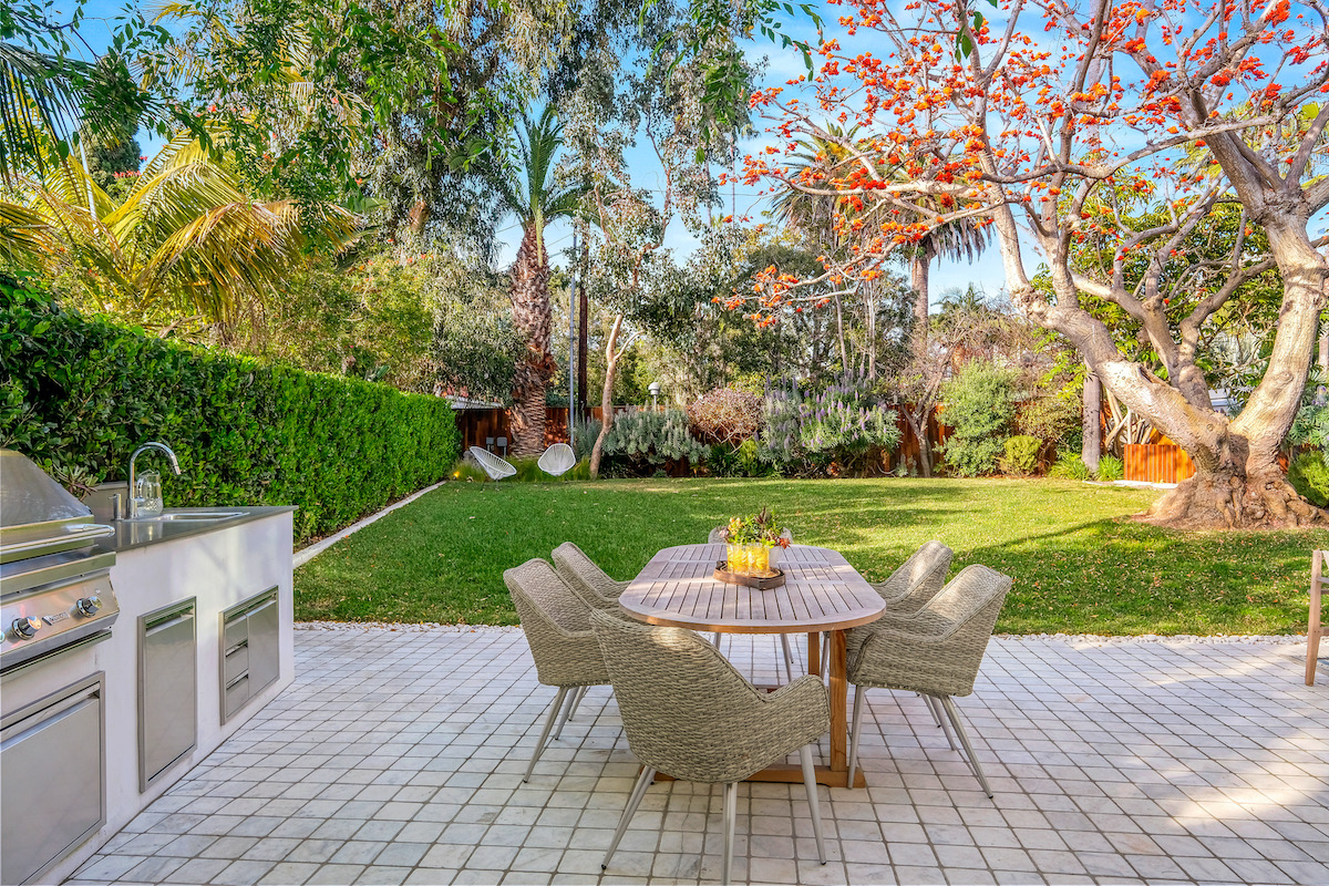 backyard patio with grassy lawn, patio table with chairs, and bbq area