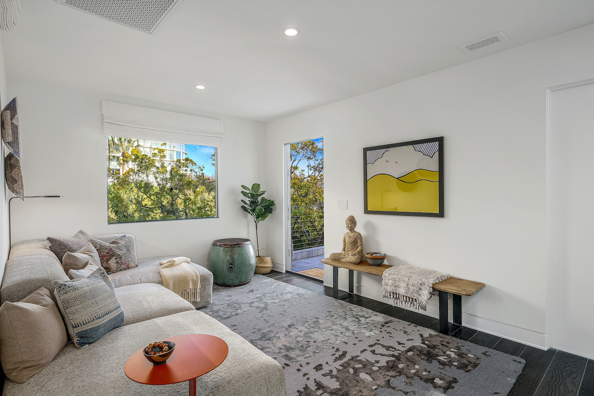 sitting area featuring a small couch and wooden table with a door leading to the outdoors