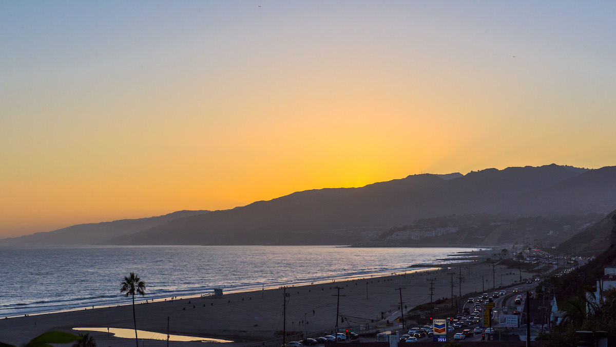 aerial view of the sunset behind the mountain with the beach in the distance