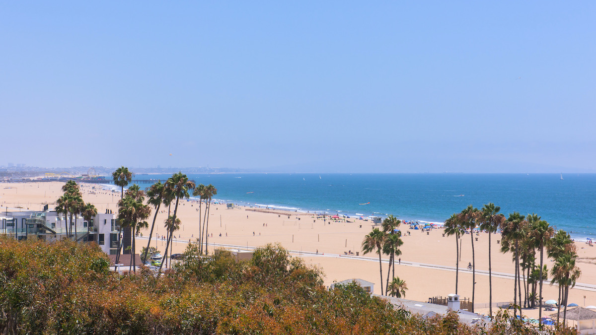 aerial views of the ocean and beach, showcasing palm trees and a walkway on the sand